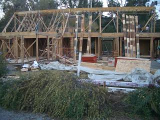 [Reused lumber roof joists being framed]